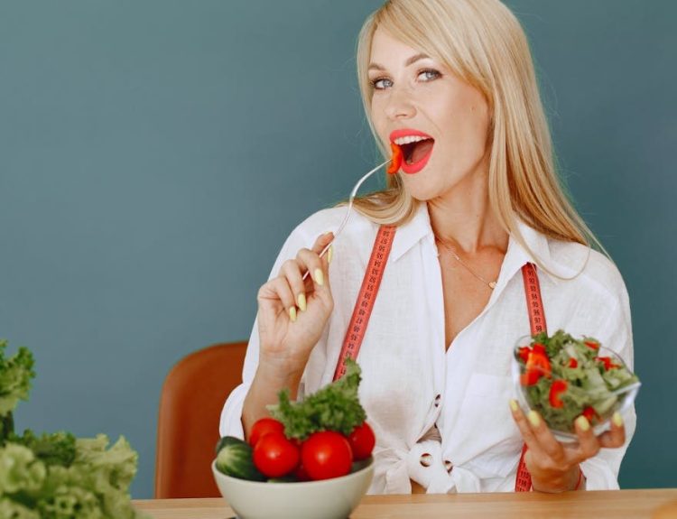 Woman enjoying a fresh salad with tomatoes and greens, promoting healthy eating.