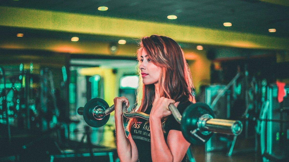 woman lifting black and gray barbell